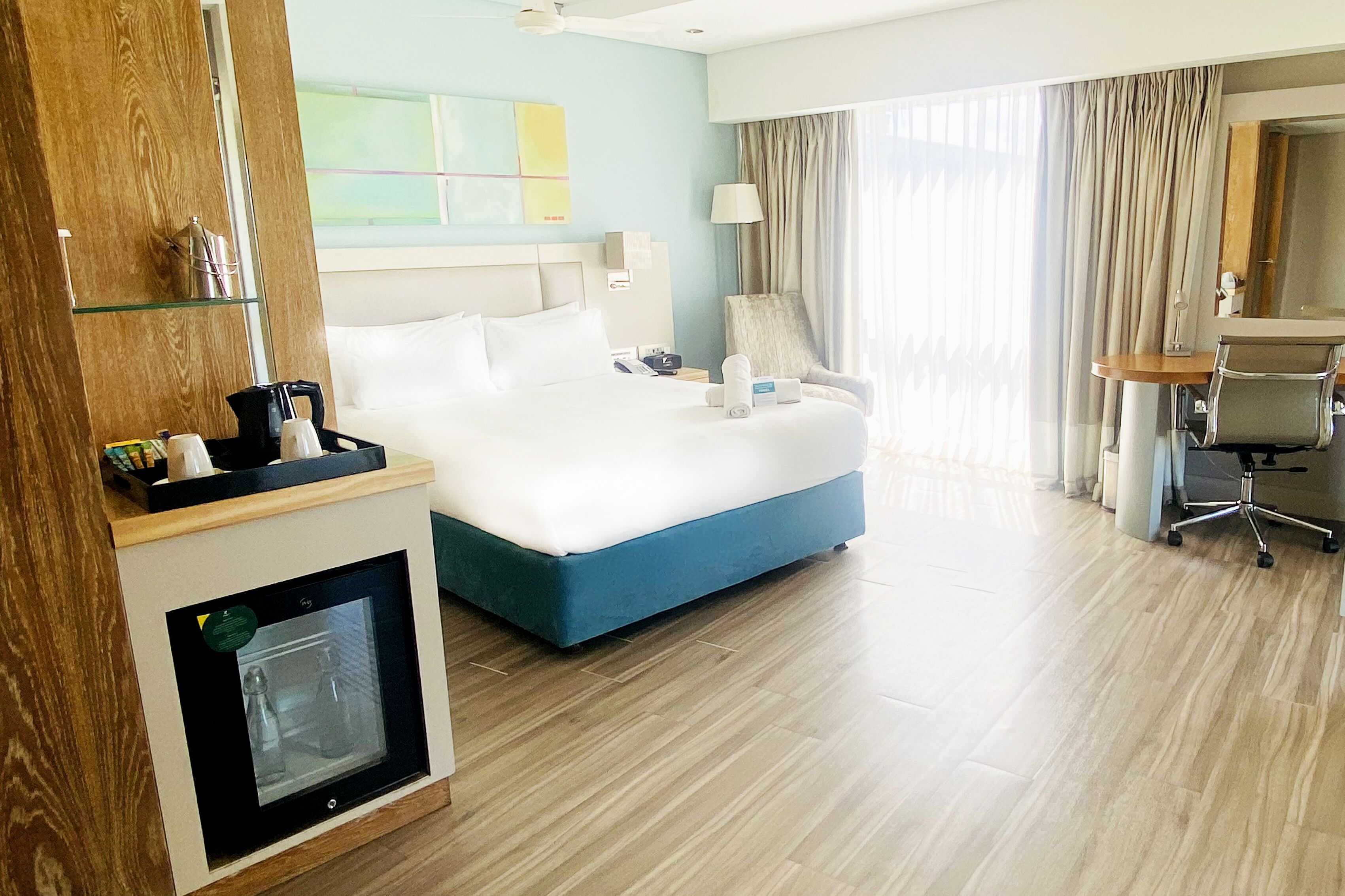 Una habitación de hotel con una cama grande, un escritorio, una silla, un minibar y una chimenea con cristal.