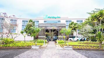 Un hotel Holiday Inn con fachada moderna, entrada principal y un jardín bien cuidado.