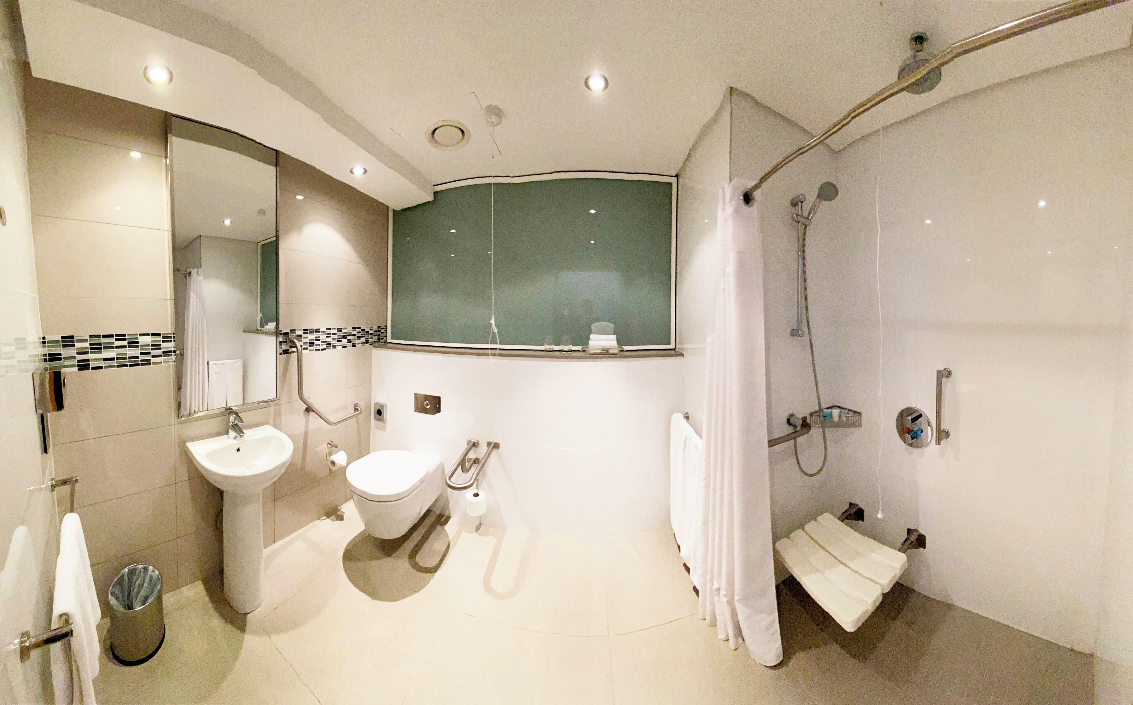 Une salle de bain moderne équipée d’un lavabo, de toilettes et d’une douche.