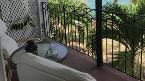 A balcony with a glass table, a white chair, and a view of the sea and mountains. - Green Roof Inn (Hillsborough)