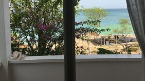 A room with a large window overlooking a beach and a garden. - Green Roof Inn (Hillsborough)