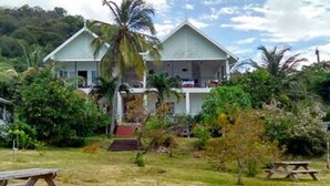 A two-story house with a porch, surrounded by lush greenery and a clear sky. - Green Roof Inn (Hillsborough)