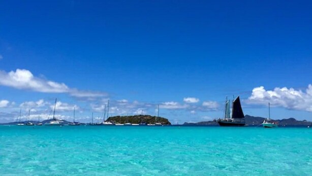 A clear turquoise sea with several sailboats and a small island in the distance. - Green Roof Inn (Hillsborough)