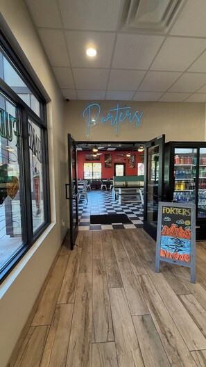 An interior of a restaurant with a neon sign reading "Porters," wooden flooring, and a menu board outside.