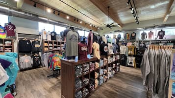 Una tienda de ropa con pisos y techo de madera, exhibiendo camisetas y ropa casual.
