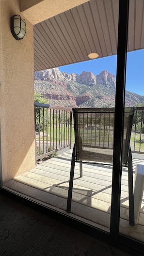 A balcony with a view of mountains, a chair, and a railing. - Bumbleberry Inn (Springdale)