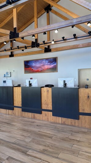 A reception desk with a wooden finish, multiple computer monitors, and a large landscape painting above.