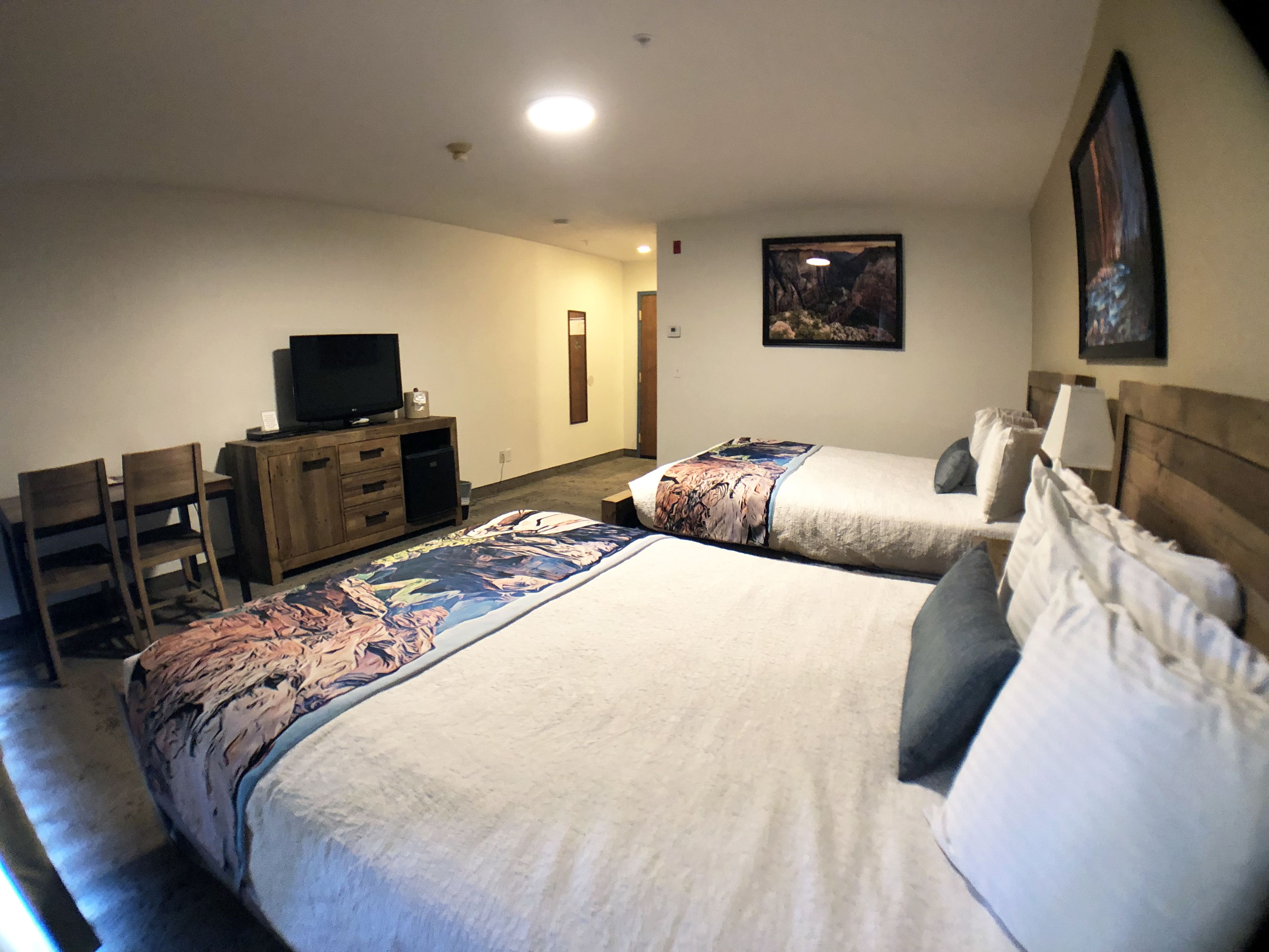 A hotel room with two beds, a TV, a desk, and a chair.