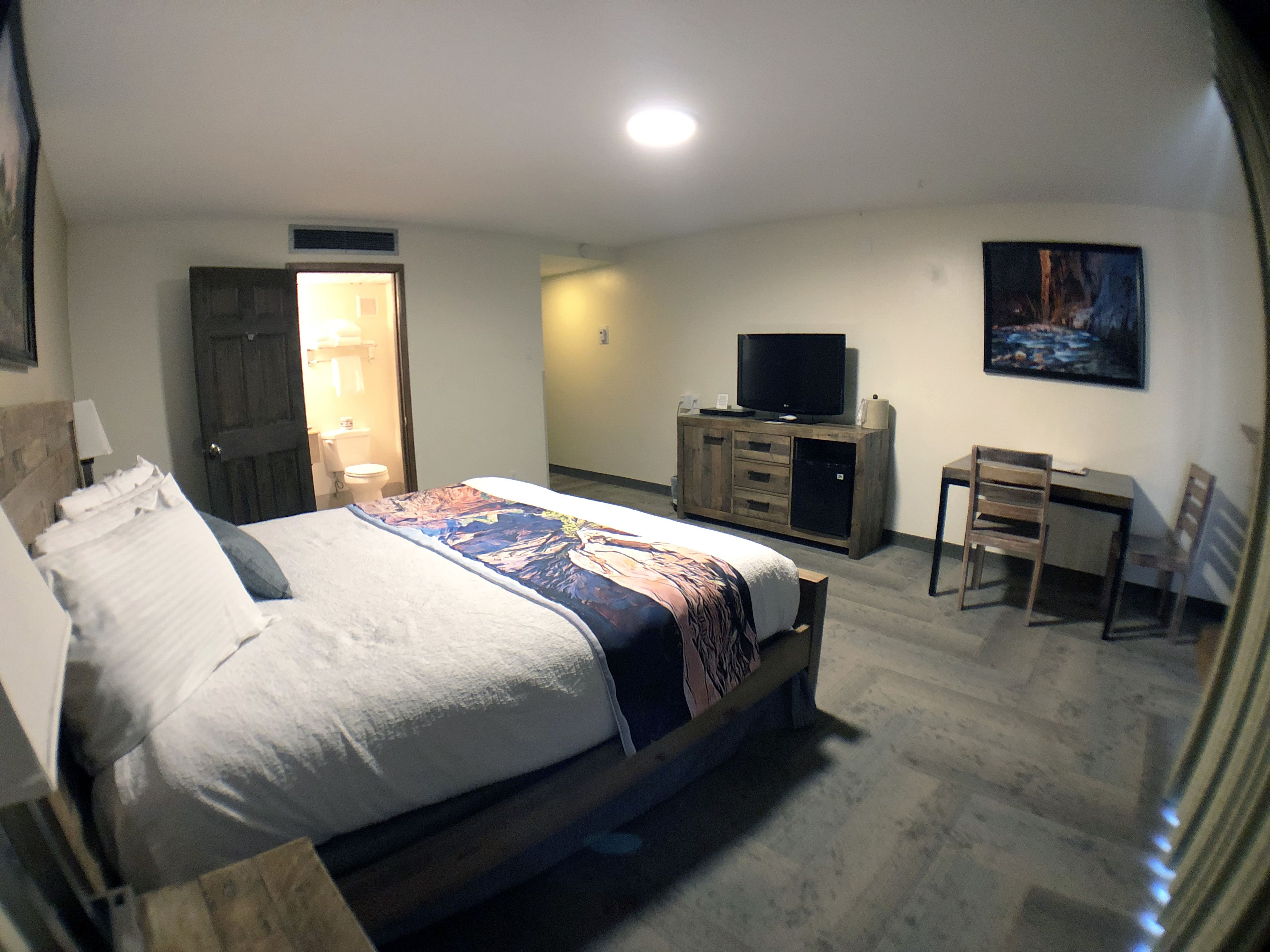 Une chambre d’hôtel avec un grand lit, une télévision, un bureau et une chaise.