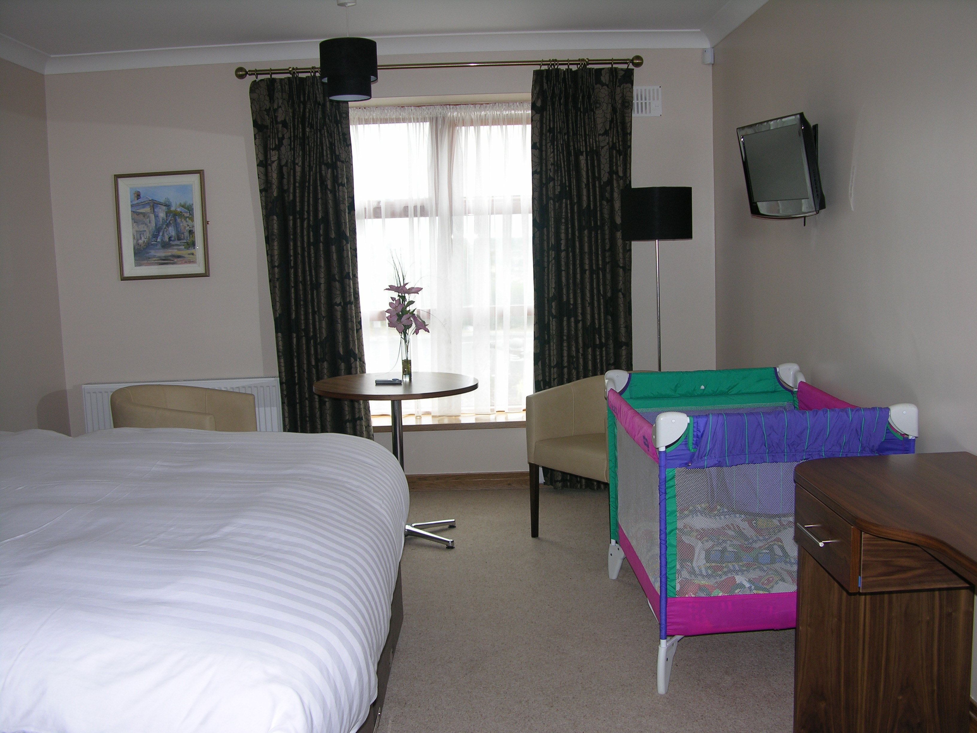 Une chambre d’hôtel avec un lit, une petite table sur laquelle est posé un vase, une chaise, un téléviseur et un lit superposé.