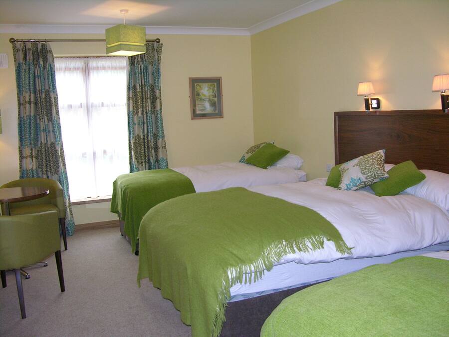 A hotel room with two beds, a chair, a desk, and a window with curtains.