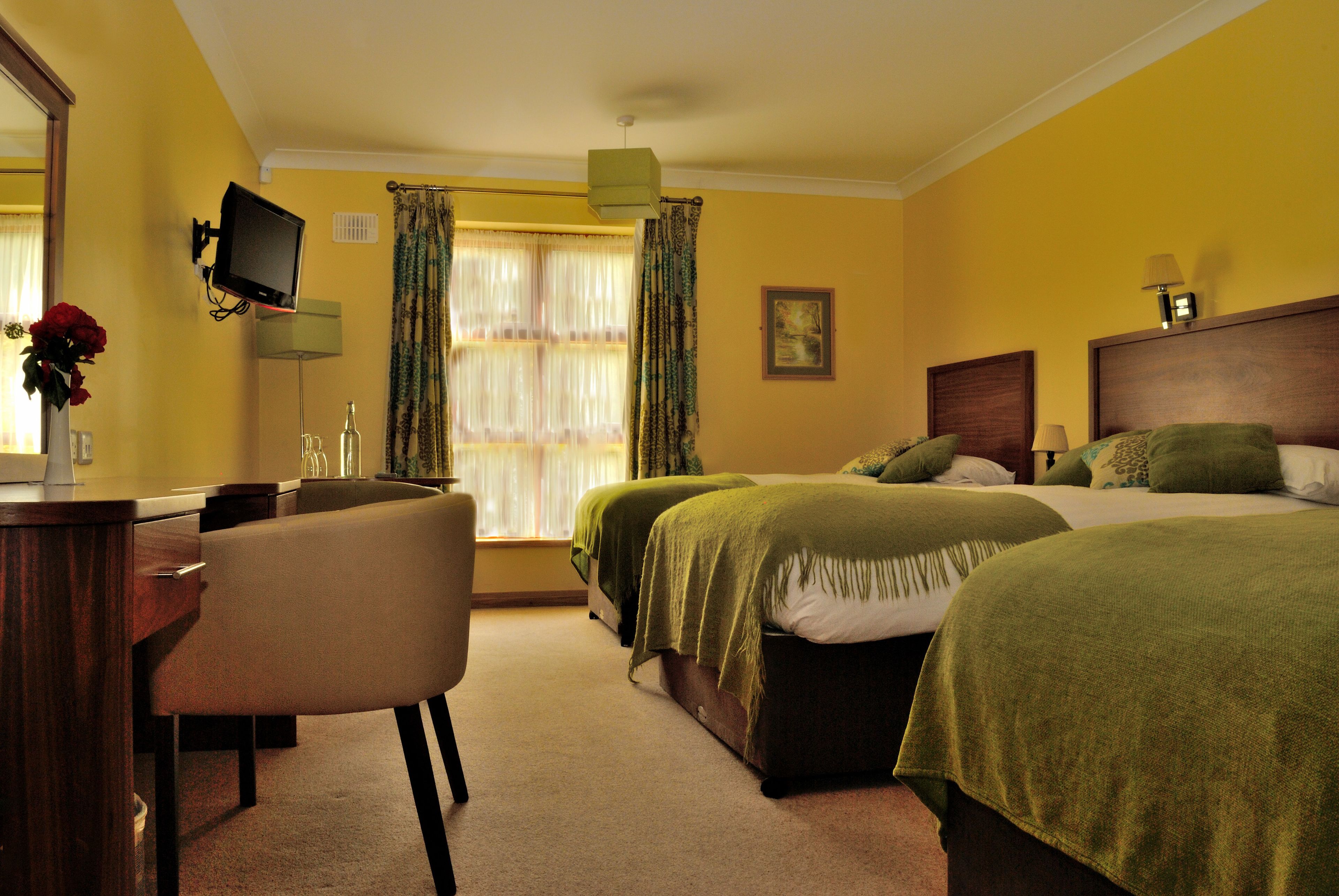 A hotel room with two beds, a desk, a chair, a television, and a window with curtains.