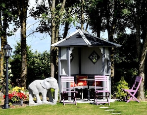 A small, white gazebo with a sloped roof, surrounded by trees. In front of the gazebo, there is a stone elephant sculpture and a table with chairs. - Kilbawn Country House (Gowran)