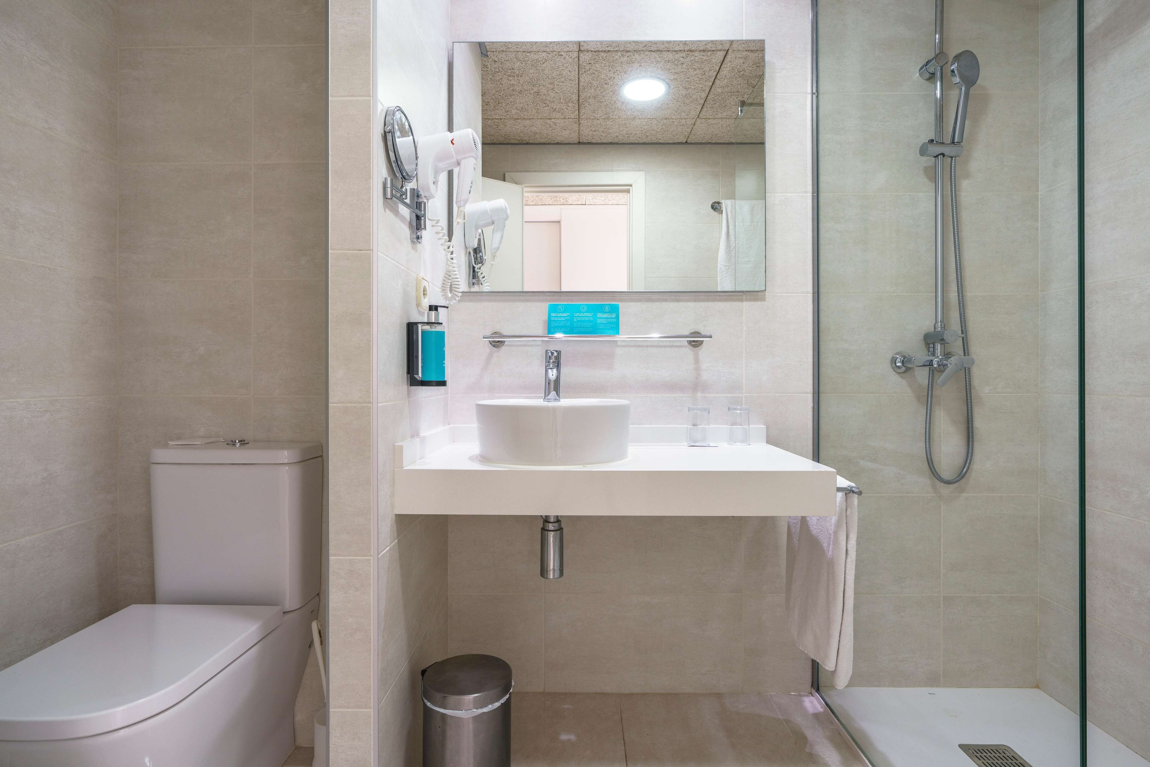 A modern bathroom with a toilet, sink, and shower.
