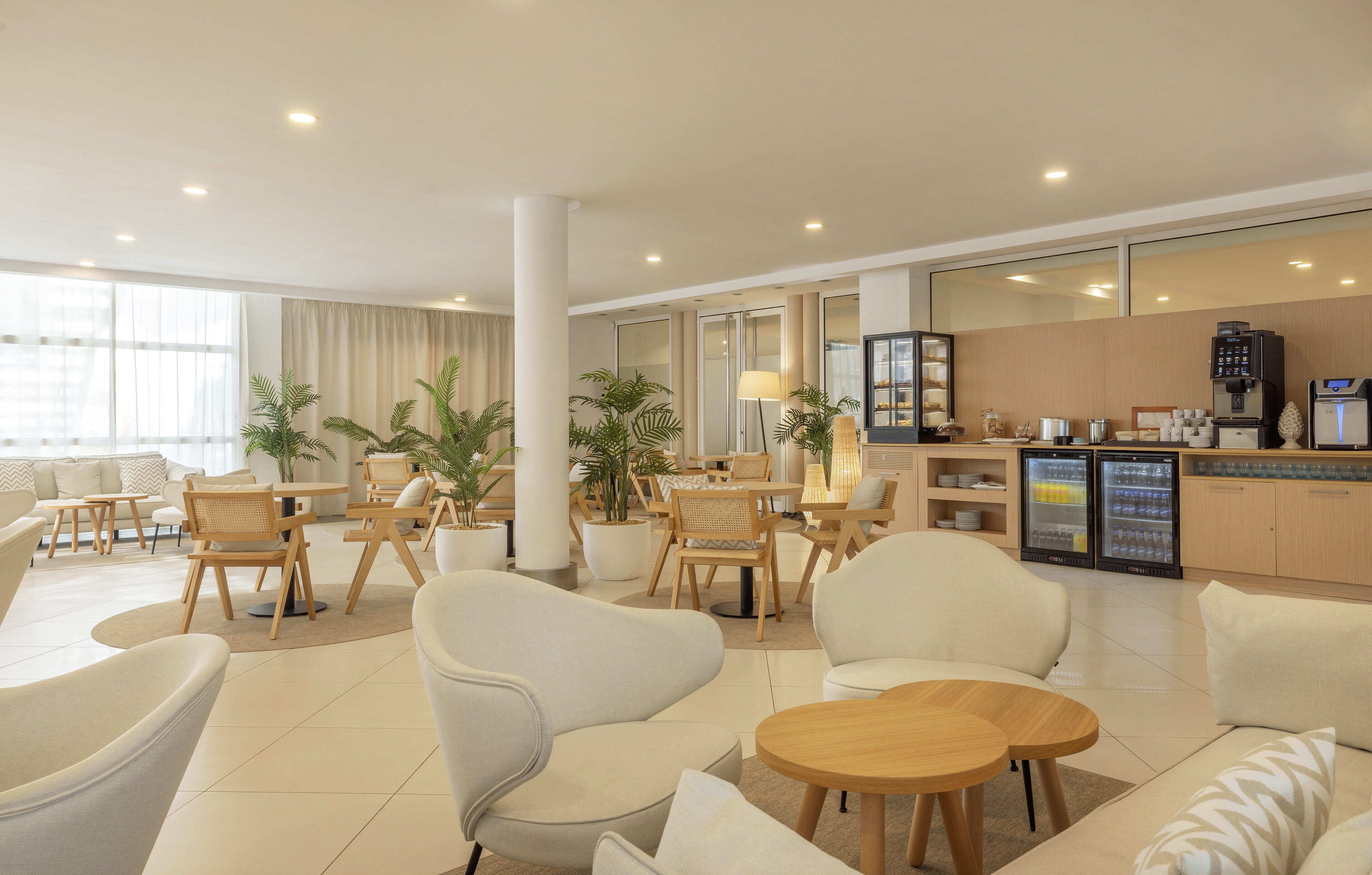 A modern hotel lobby with seating areas, a reception desk, and a kitchenette.