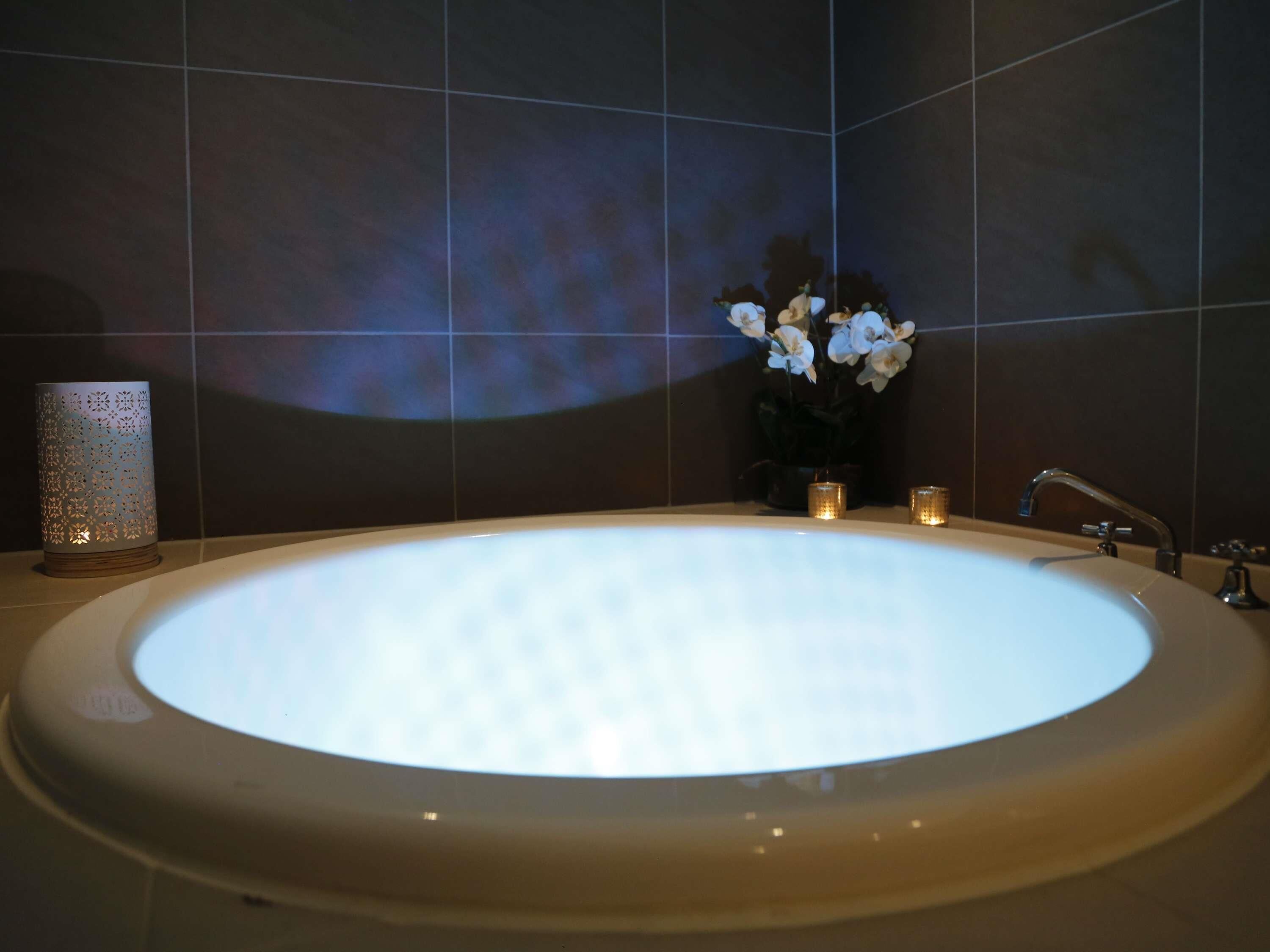 A modern bathroom with a large oval sink, a wall-mounted mirror, and a potted plant with white flowers.