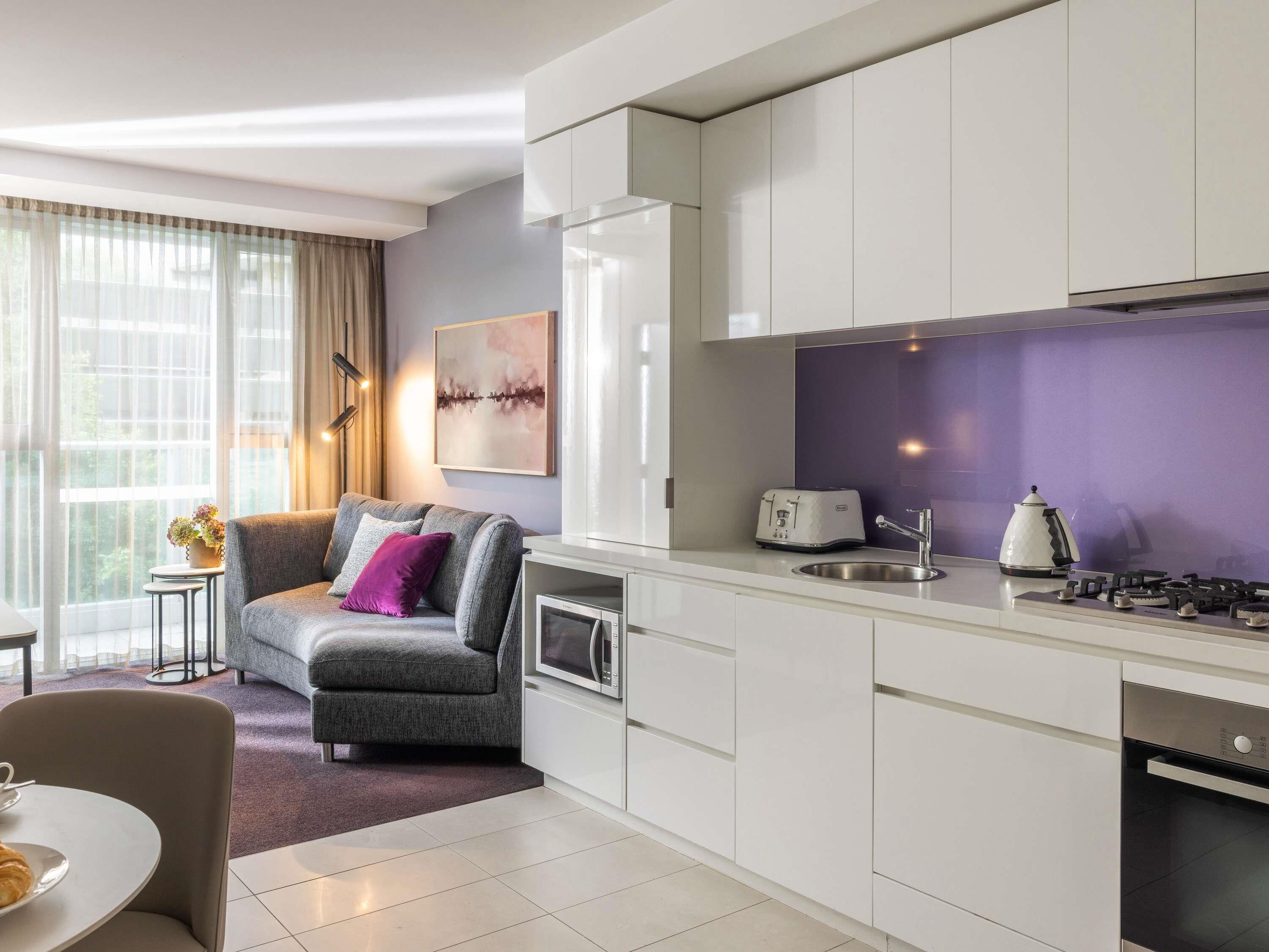 A modern kitchen with white cabinets, a gas stove, a microwave, and a toaster.