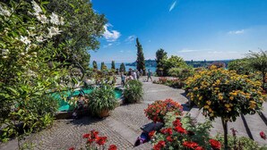 A garden with a pool, various plants, and a view of the city. - Hotel Waldblick (Donaueschingen)