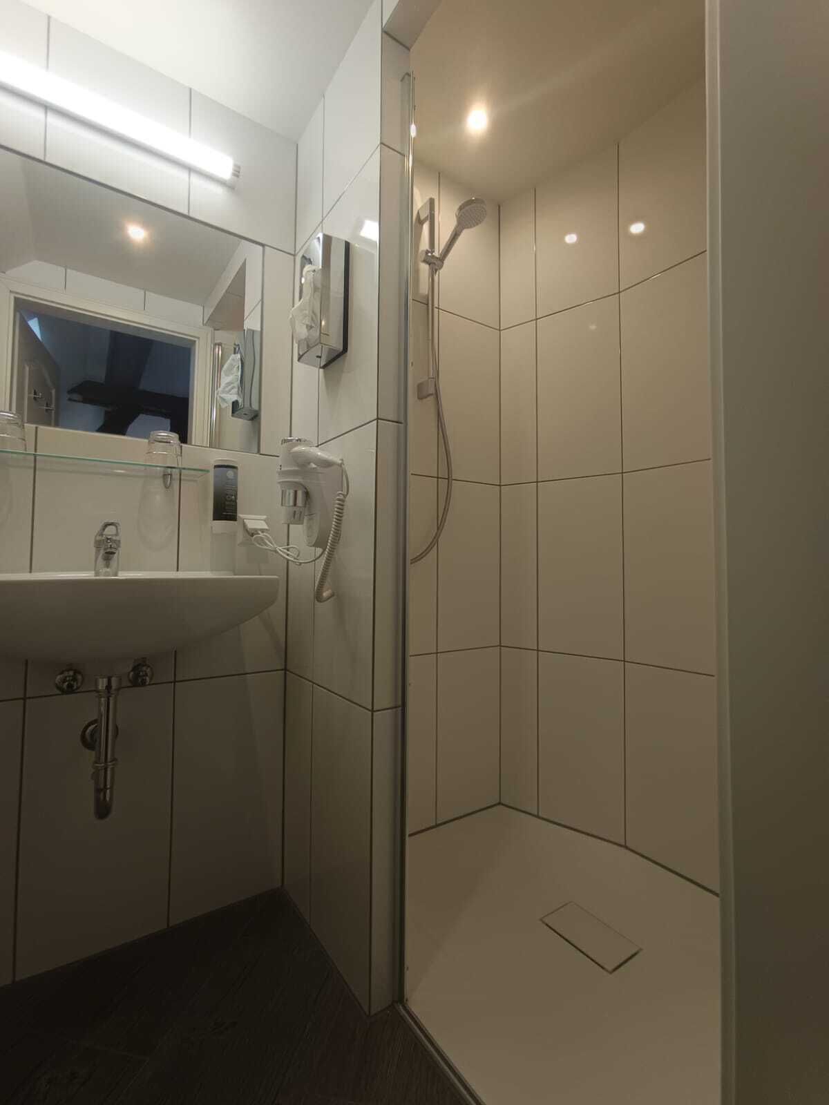 A modern bathroom with a glass-enclosed shower, a sink, and a mirror.