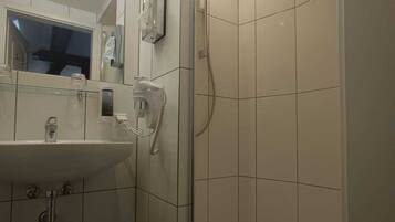 A modern bathroom with a glass-enclosed shower, a sink, and a mirror.
