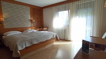 Ein Hotelzimmer mit einem großen Bett, zwei Nachttischen, einem Schreibtisch und einem Sessel.