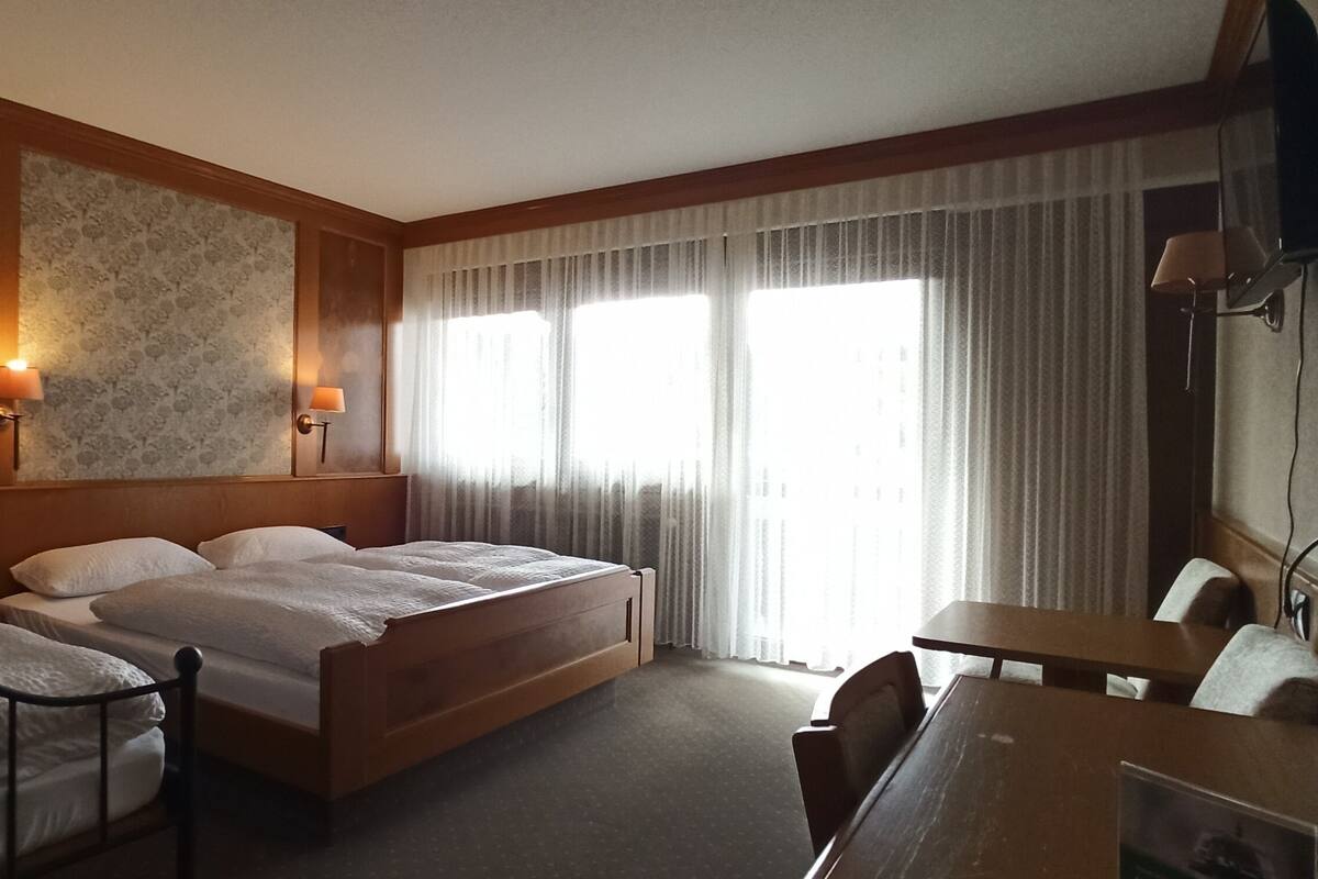 A hotel room with two beds, a desk, and a TV.