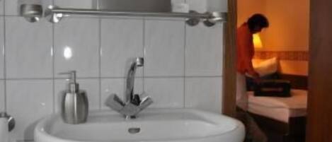 A bathroom with a white sink, a mirror, and a towel rack.