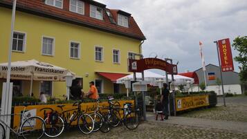 Un edificio amarillo con techo rojo, un cartel que dice 'Hofgarten Restaurant & Biergarten' y un letrero de 'Hotel'.