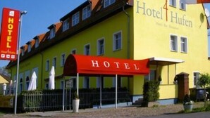 A yellow building with a red awning labeled "HOTEL Hufen." - Hotel 4 Hufen (Schoenefeld)