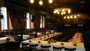 A restaurant with long tables set for dining, chairs, and a chandelier. - Hotel 4 Hufen (Schoenefeld)