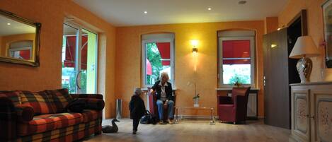 Una sala de estar con un sofá, un sillón rojo, un aparador y un espejo grande.