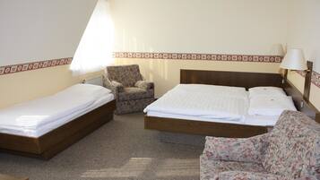 Quarto com duas camas de solteiro, uma poltrona estampada e cabeceira de madeira.