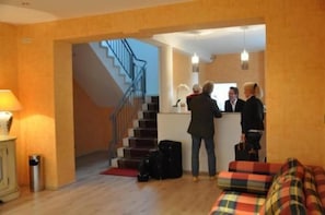 A reception area with a staircase, a reception desk, and a sofa. - Hotel 4 Hufen (Schoenefeld)