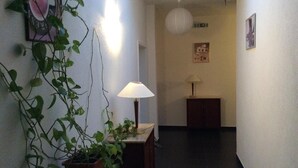 A hallway with a potted plant, a lamp, and a cabinet. - Hotel-12-Apostel (Pforzheim)