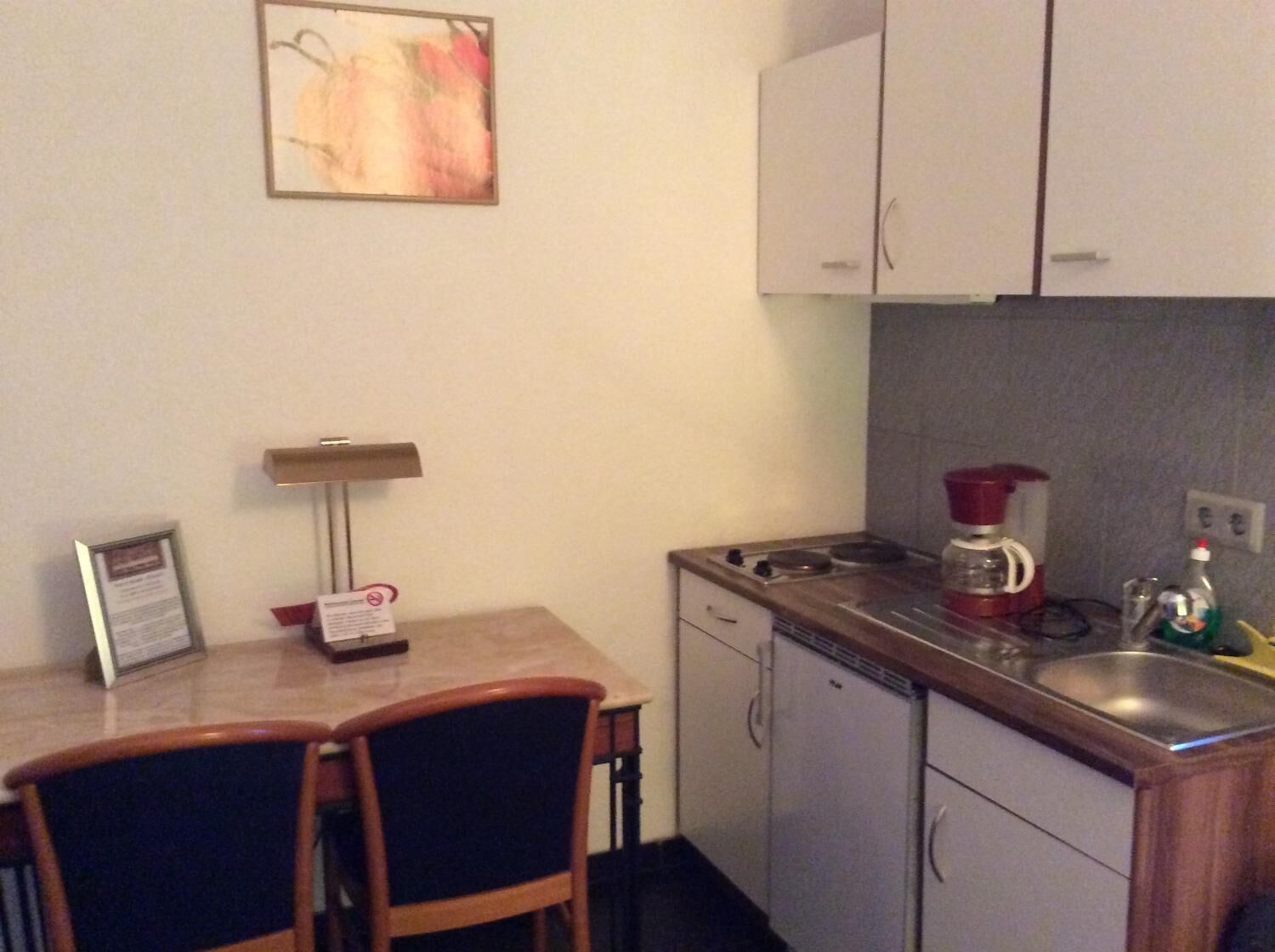 A compact kitchen with a coffee maker, a sink, and cabinets.