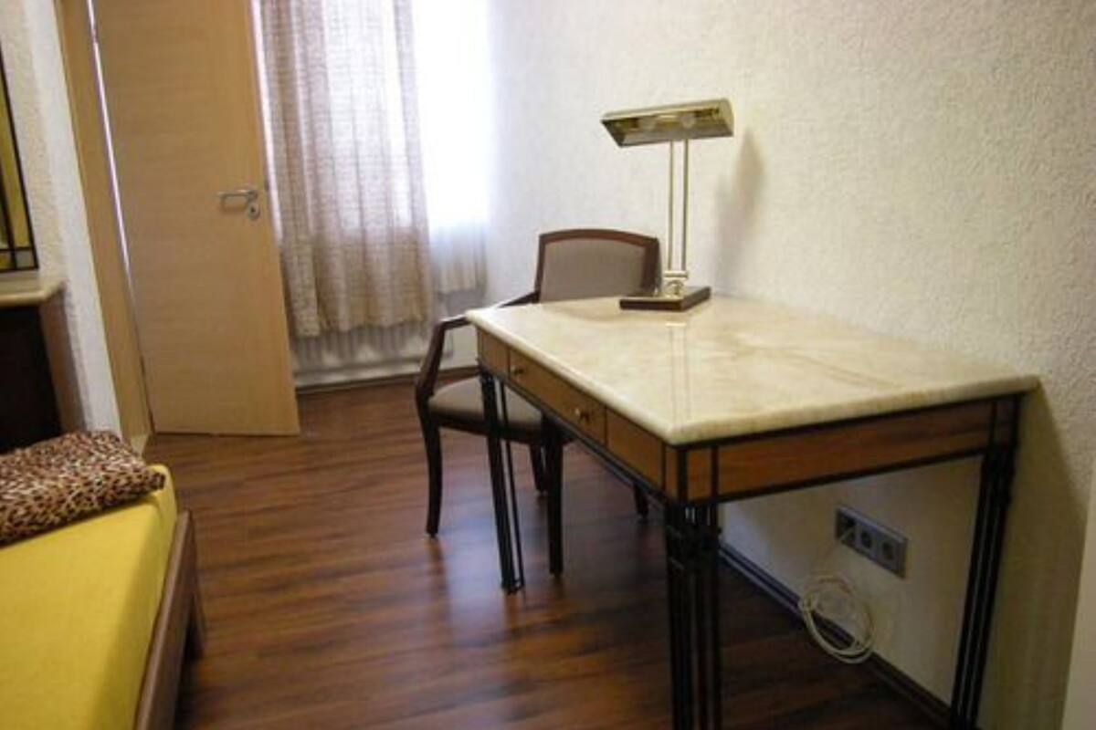 A room with a wooden desk, a chair, a lamp, and a bed with a leopard print cover.