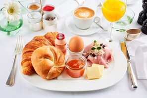 A breakfast plate with croissants, eggs, ham, cheese, and condiments. - Hotel-12-Apostel (Pforzheim)