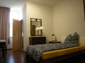 A bedroom with a zebra-patterned bed, a bedside lamp, a mirror, and a small table. - Hotel-12-Apostel (Pforzheim)