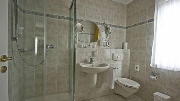 A bathroom with a glass-enclosed shower, a sink, a toilet, and a mirror.