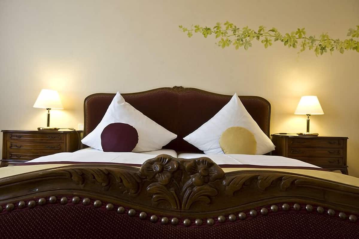 A neatly made bed with a wooden headboard, two bedside tables with lamps, and a wall-mounted plant.