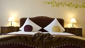 A neatly made bed with a wooden headboard, two bedside tables with lamps, and a wall-mounted plant.