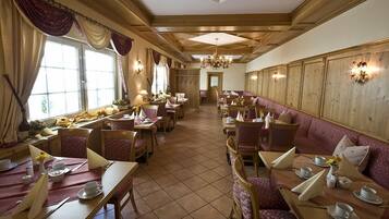 Une auberge traditionnelle avec des boiseries, un lustre et un mélange de tables à manger et d’espaces salon.