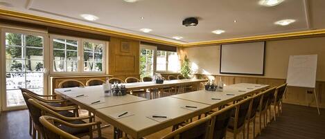 Une salle de conférence équipée d’une longue table, de chaises, d’un écran de projection et d’un tableau blanc.