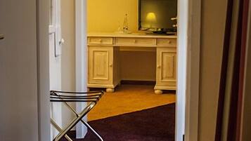 A narrow hallway leading to a kitchen with white cabinets and a television.