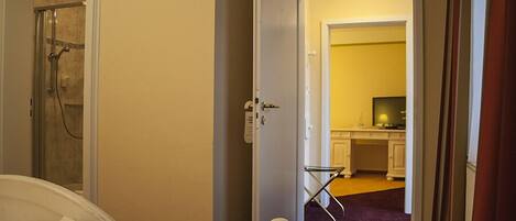 Un dormitorio con cama, ducha y puerta abierta que da a una zona de cocina.