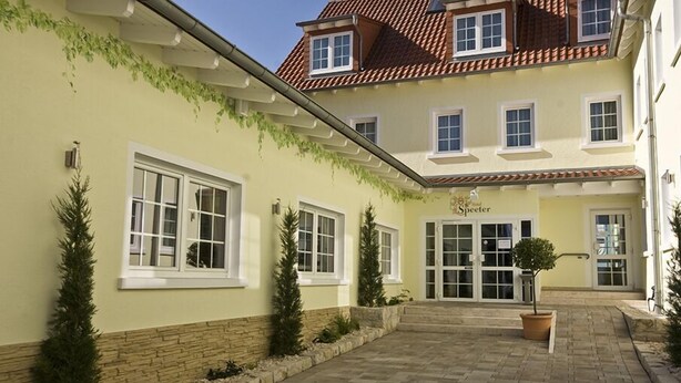 A hotel with a yellow facade, a red-tiled roof, and a central entrance with glass doors. - Hotel Restaurant Speeter (Weisenheim am Berg)