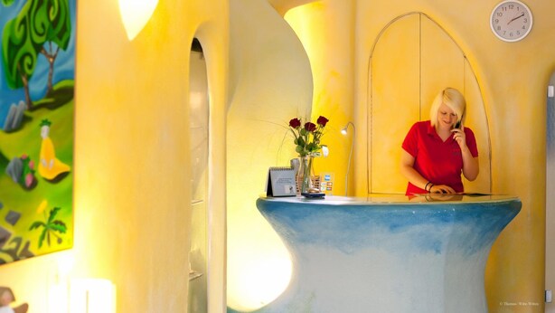 Ein Empfangsbereich mit Blumenvase, einer Uhr und einem Gemälde an der Wand.