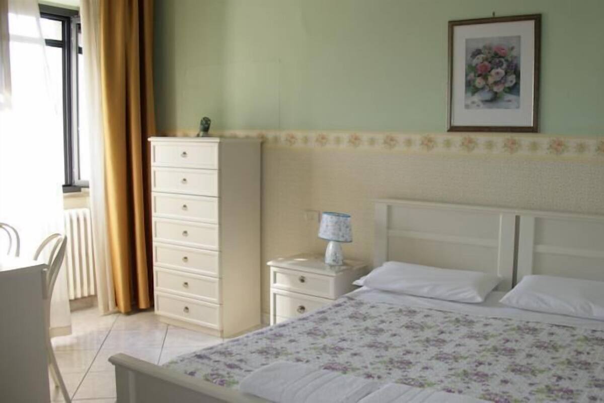 Un dormitorio con cama, cómoda, mesita de noche y un cuadro en la pared.