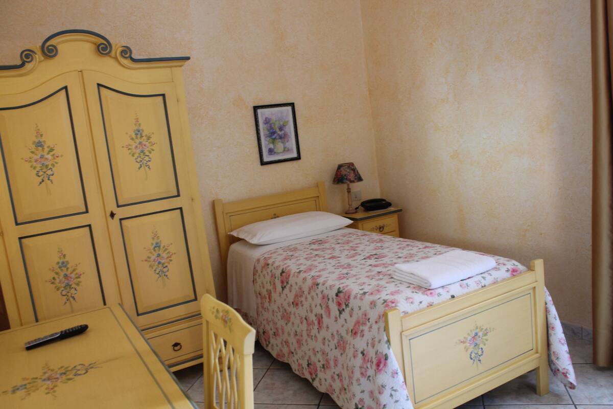 Un dormitorio con cama, mesita de noche, cómoda y una silla.
