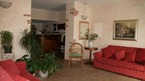 Una sala de estar con un sofá rojo, una silla de madera y plantas en macetas.